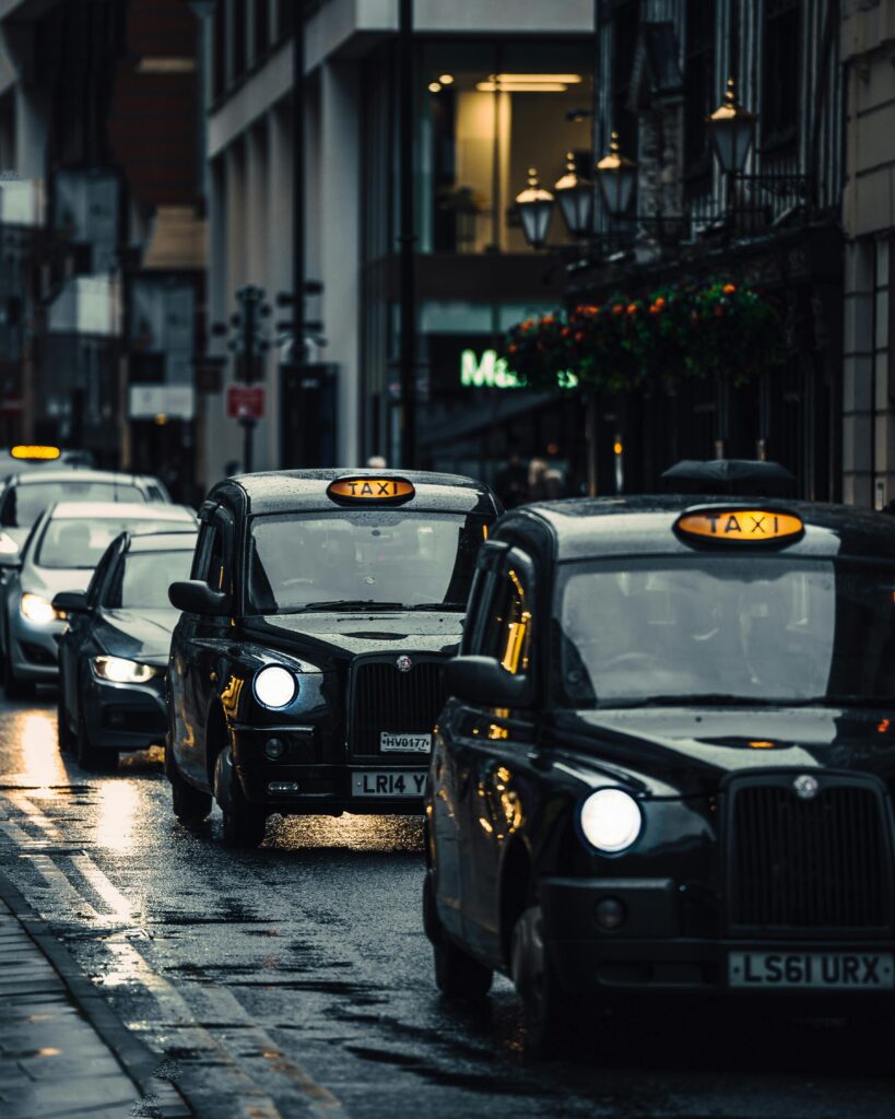 Classic London taxis navigating wet streets in an atmospheric cityscape.